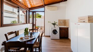 Een kleine keuken met een wasmachine, een eettafel met stoelen en uitzicht door het raam.