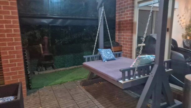 Une terrasse avec une chaise suspendue et une petite table.