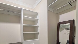 Un dressing accessible sans porte, doté d’étagères ouvertes, d’une porte-miroir et d’un meuble de rangement noir.