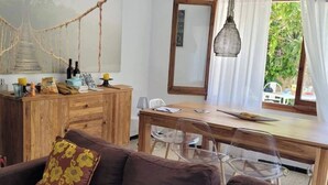 A cozy living area with a wooden cabinet, a dining table, and a sofa with floral cushions.