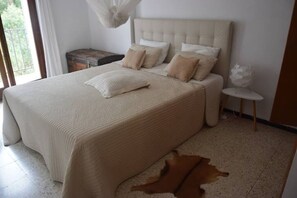 A bedroom with a large bed, a headboard, and a small bedside table. - Between Land and Sea - A Quiet House in Rosamar (Canyet de Mar)