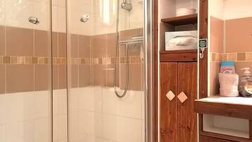 Un baño moderno con ducha acristalada, muebles de madera y suelo de baldosas.