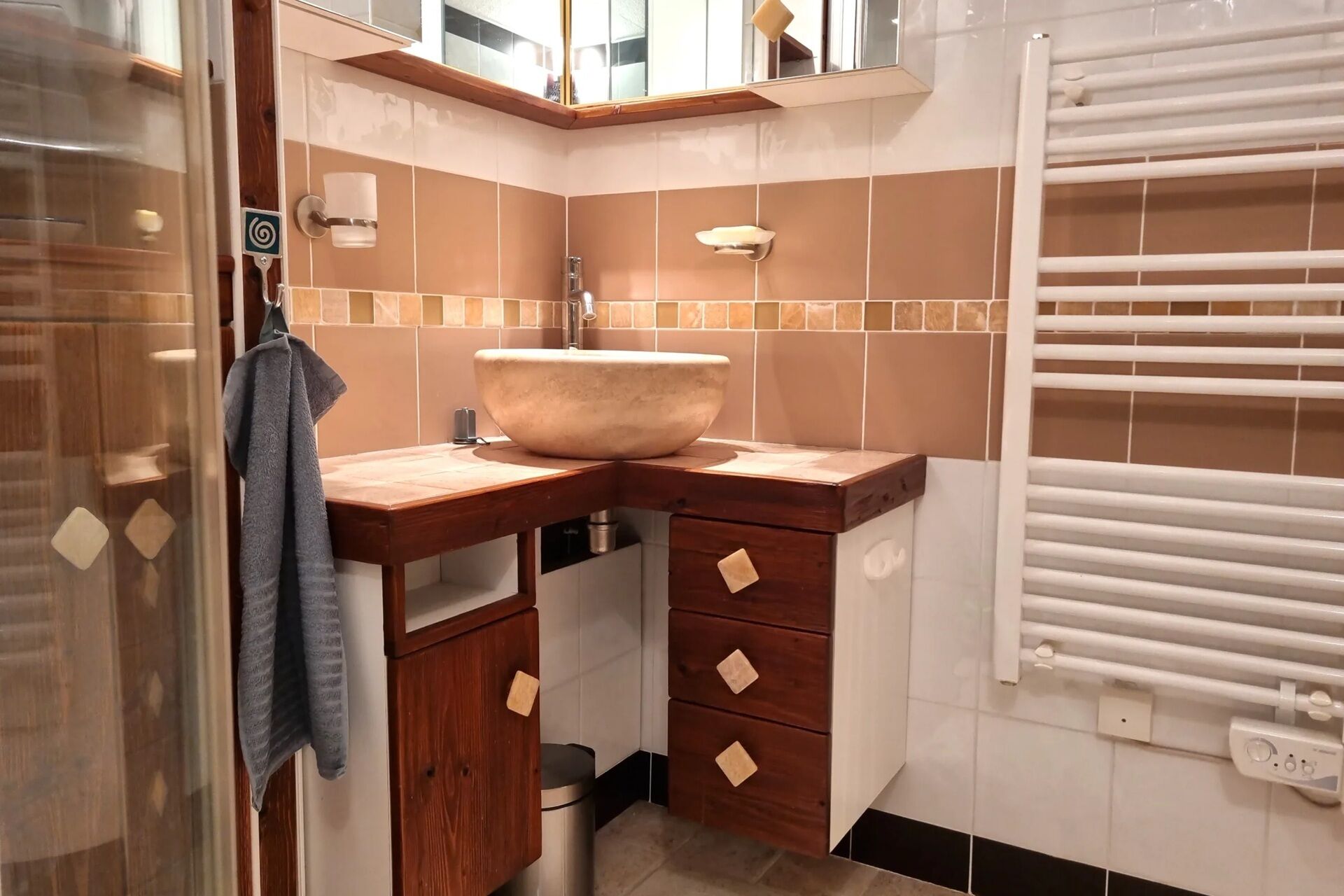 Une salle de bain avec un grand lavabo sur pied, des meubles en bois, un porte-serviettes et une serviette qui y est accrochée.