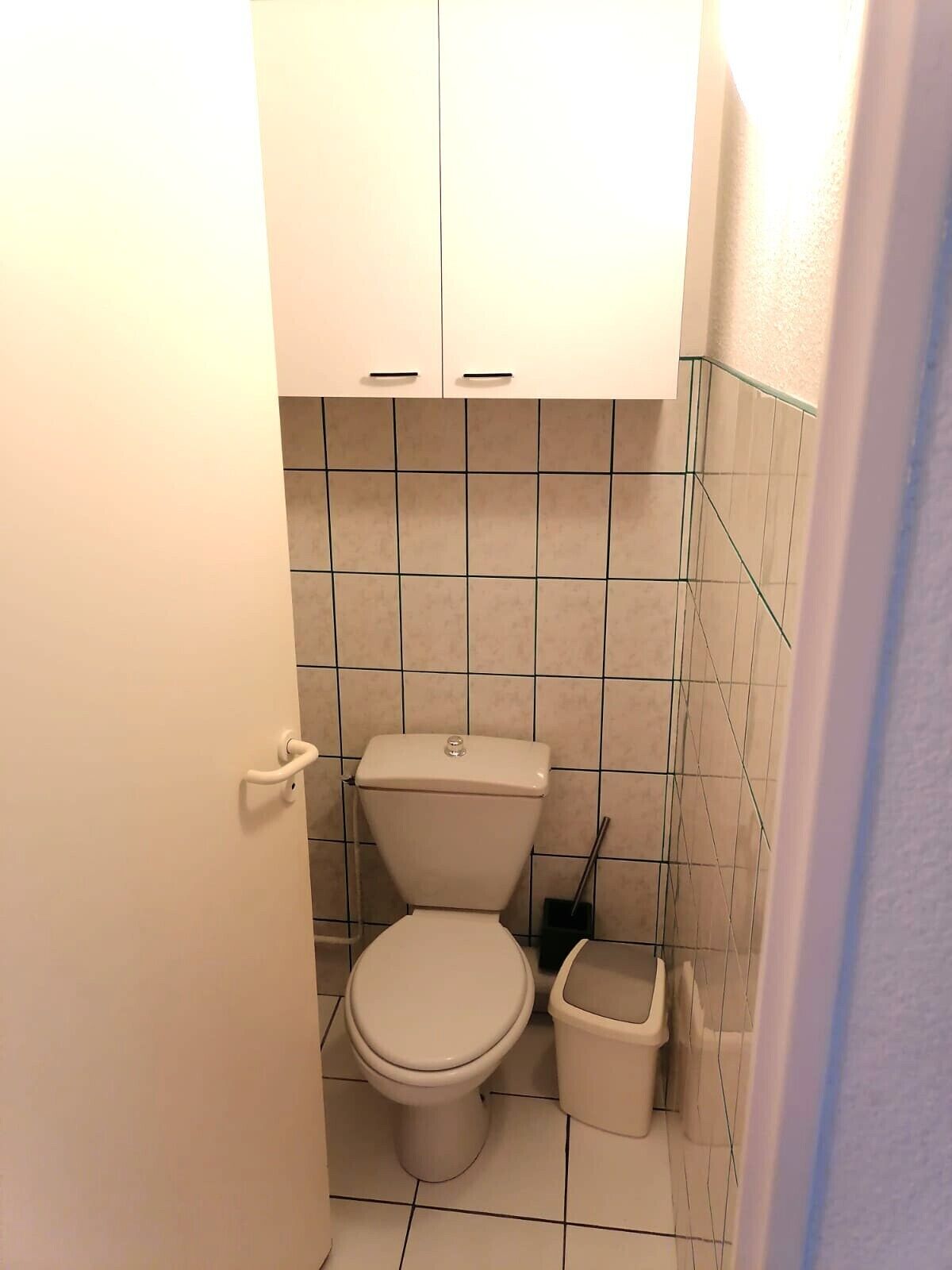 A small, clean bathroom with a toilet, a bidet, and a trash bin.
