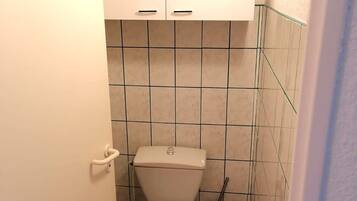 A small, clean bathroom with a toilet, a bidet, and a trash bin.