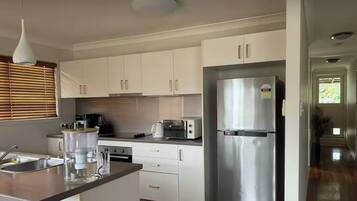 A modern kitchen with white cabinets, stainless steel appliances, and a wooden countertop.
