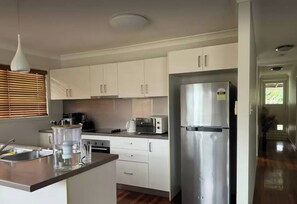 A modern kitchen with white cabinets, stainless steel appliances, and a wooden countertop. - Room-room in a Beautiful Queenslander Ho (Brisbane)