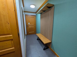A hallway with a wooden door, a bench, and a wall with vertical slats.