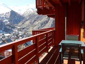 Varanda de madeira com vista para uma cidade e montanhas.