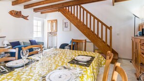 Un coin repas agrémenté d’un escalier en bois, d’une décoration marine et d’une table dressée pour quatre personnes.