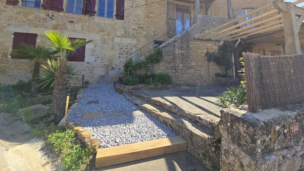 A stone building with a wooden staircase and a gravel pathway.