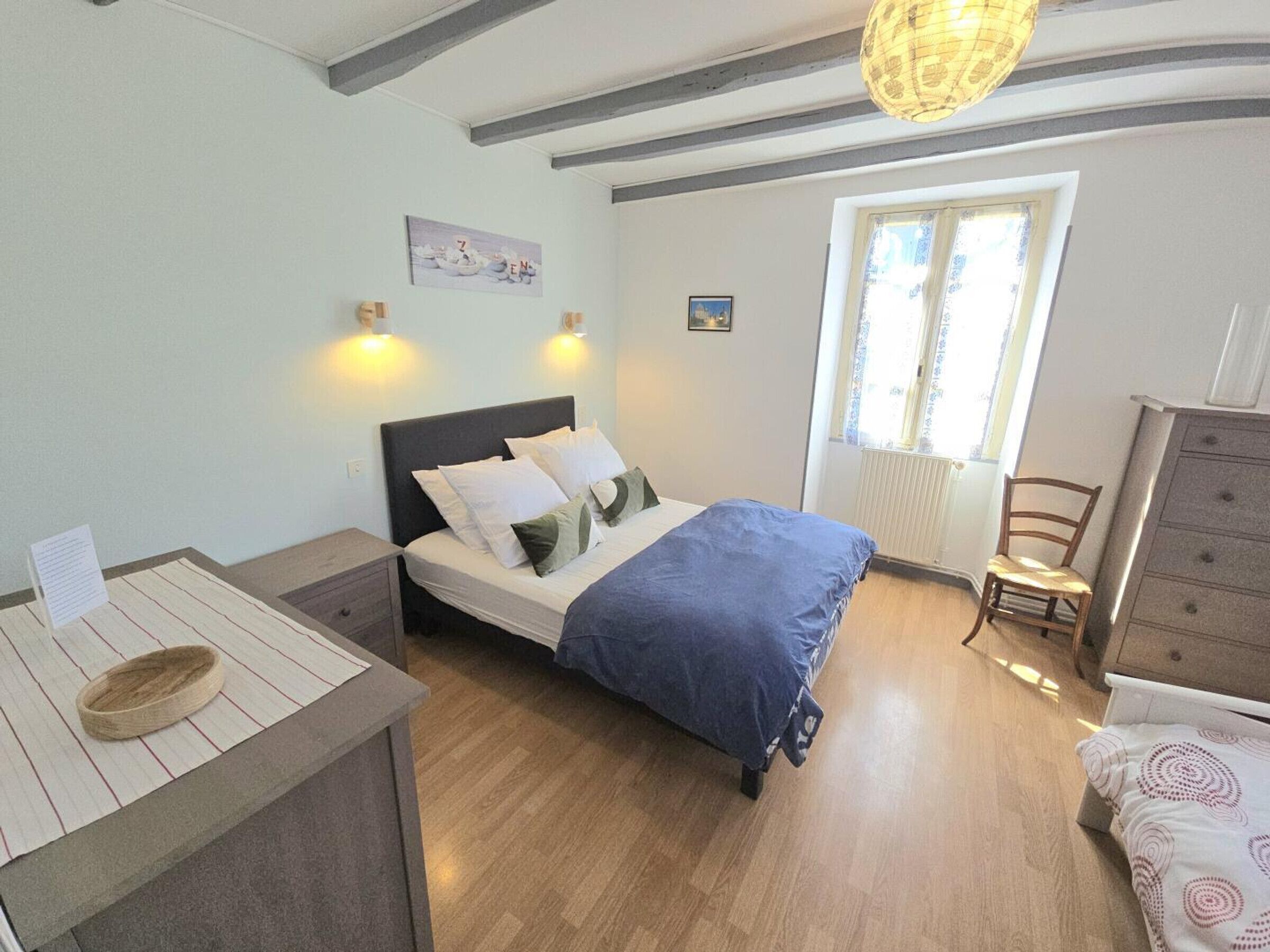A bedroom with a bed, bedside tables, a dresser, a chair, and a window with curtains.