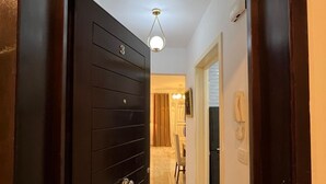 Un passadís amb una porta de fusta fosca, un paviment de marbre i un llum al sostre.
