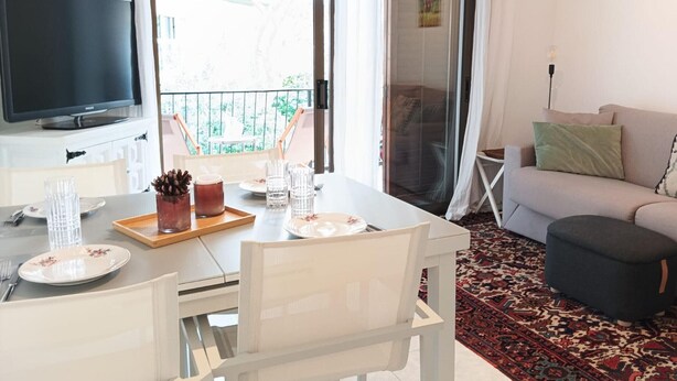 En moderne stue med spiseplads, et fladskærms-tv og en balkon med udsigt.