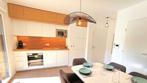 A modern kitchen with white cabinets, a microwave, and a dining area with a white table set for four.