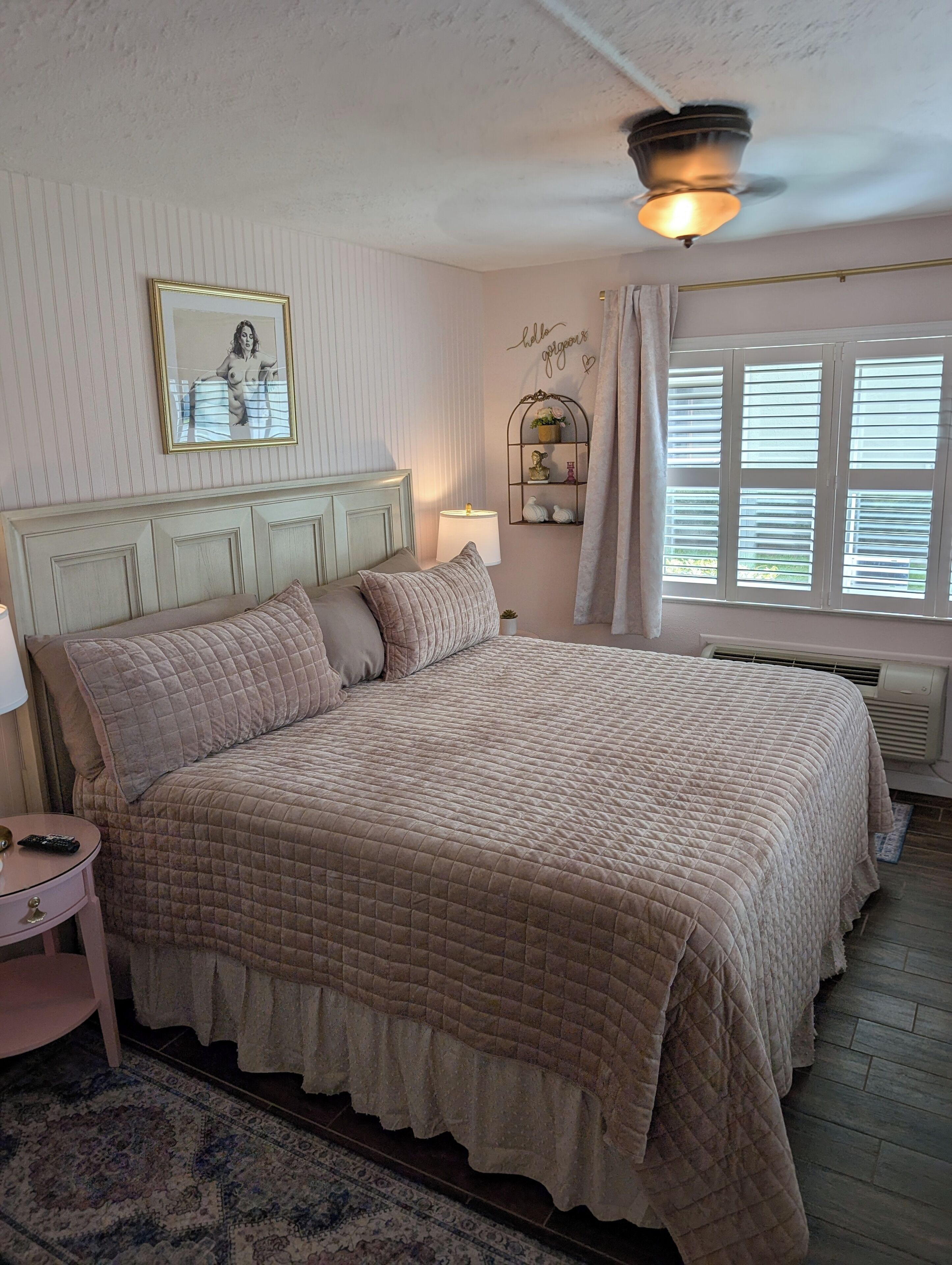 Une chambre à coucher avec un lit, une table de chevet, une lampe et une fenêtre avec des stores.