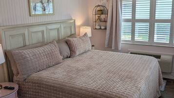 Une chambre à coucher avec un lit, une table de chevet, une lampe et une fenêtre avec des stores.