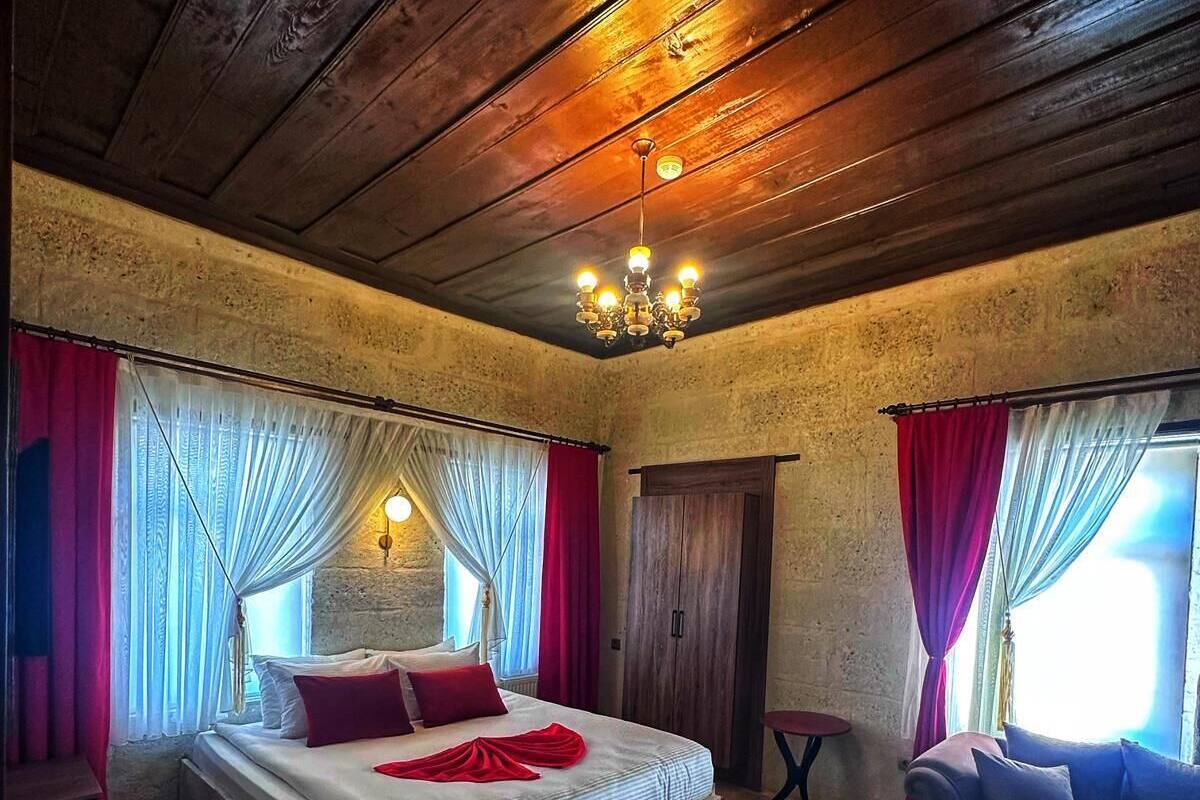 A bedroom with a large bed, a sofa, a small table, and a chandelier.