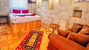A room with a bed, a sofa, a small table, and a rug. - CRİMSON CAPPADOCİA (Avanos)