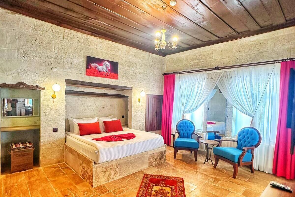 A cozy bedroom with a bed, a small table, two chairs, a rug, and a view of the outside.