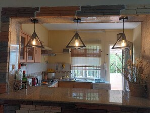 A kitchen with granite countertops, a central island, hanging pendant lights, and a view of the outdoors through a window with blinds. - Romantic, peaceful apartment just minutes from Péreybere, Mauritius (Pereybere)