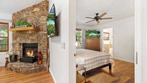 Une pièce avec une cheminée en pierre, un lit et un ventilateur de plafond.