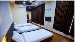 A hotel room with two beds, a flat-screen TV, and a large window with curtains. - Twilight Inn (Chennai)