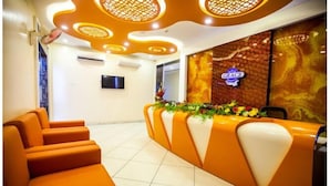 A reception area with orange seating, a floral arrangement, and a 'GRACE' sign on the wall. - Twilight Inn (Chennai)