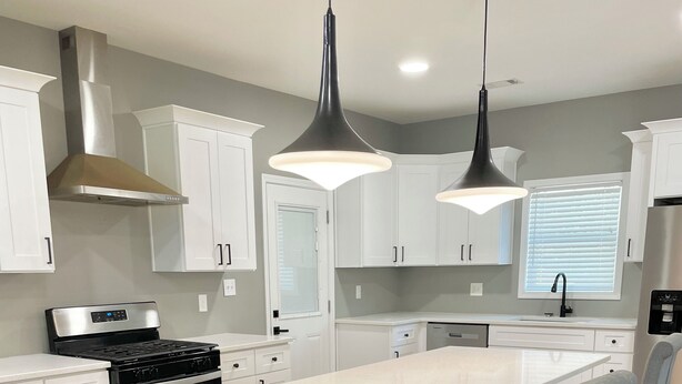 A modern kitchen with white cabinets, a central island with bar stools, stainless steel appliances, and pendant lighting. - Lovely 3-bedroom house with AC in vibrant Atlanta (Atlanta)