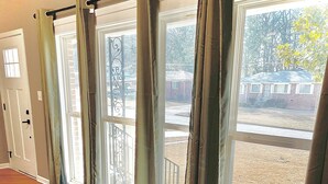 A room with large windows, wooden flooring, and a view of a residential area. - Lovely 3-bedroom house with AC in vibrant Atlanta (Atlanta)