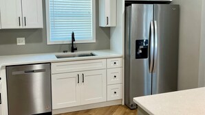 A modern kitchen with white cabinetry, a stainless steel refrigerator, and a dishwasher. - Lovely 3-bedroom house with AC in vibrant Atlanta (Atlanta)