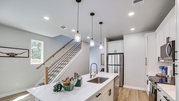 A modern kitchen with a central island, stainless steel appliances, and pendant lighting.