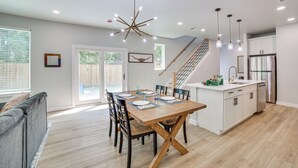 A modern kitchen with a wooden dining table, white cabinets, and a stainless steel refrigerator.
