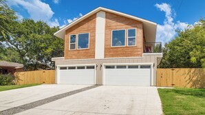 A two-story house with a garage, a wooden exterior, and a well-maintained lawn.