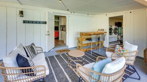 A cozy living area with wicker furniture, a dining table, and a kitchen in the background. - 5 Blocks to Jax Beach: Getaway w/ Patio & Yard! (Jacksonville Beach)