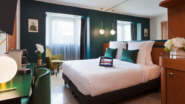 A hotel room with a large bed, a desk with a lamp, a chair, and a TV. - Street-facing Apartment in Cannes (Cannes)
