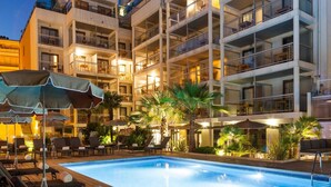 A multi-story hotel with a swimming pool, outdoor seating, and palm trees. - Street-facing Apartment in Cannes (Cannes)