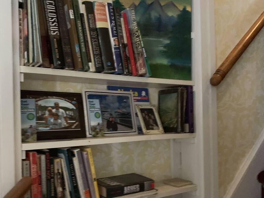 A bookshelf with various books and a framed picture.