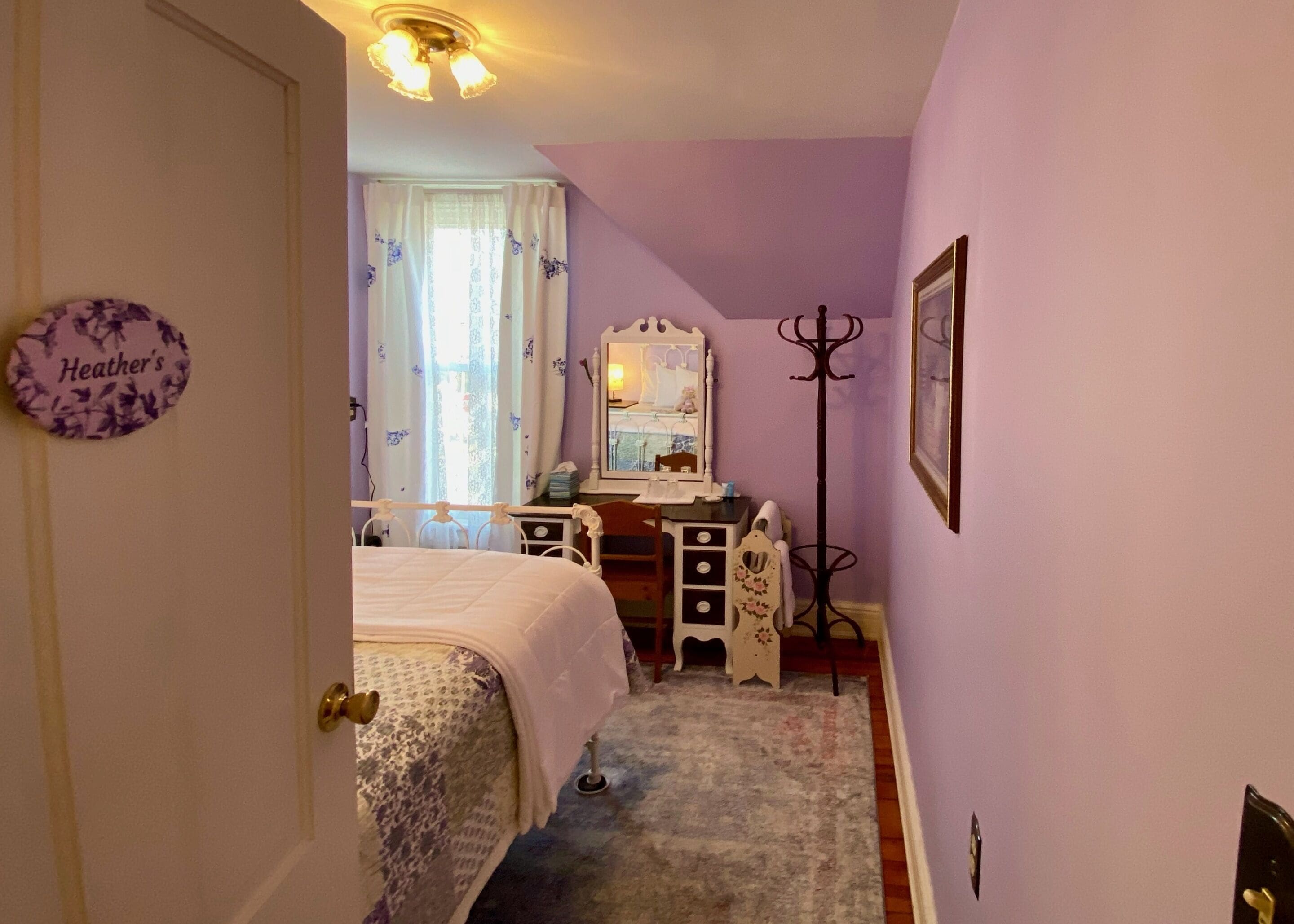 Un dormitorio con cama, cómoda, espejo y perchero.