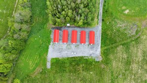 An aerial view of a parking lot with six red-roofed buildings, surrounded by greenery.