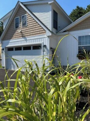 A two-story house with a garage, surrounded by greenery.