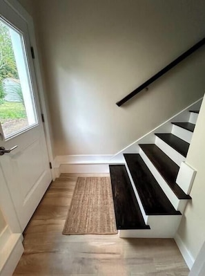 Una escalera con acabado de madera oscura y peldaños blancos, que conduce a un piso superior.