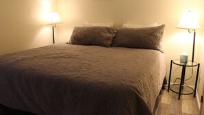Un letto rifatto con una coperta a fantasia, due abat-jour e un quadro appeso al muro.