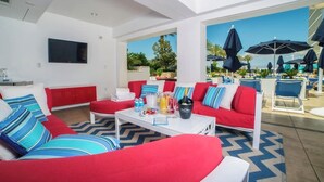 A modern living room with red sofas, a white coffee table, and a large TV on the wall.