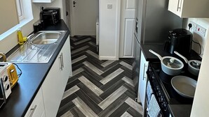 Uma cozinha moderna com piso em padrão herringbone, eletrodomésticos de aço inoxidável e um lustre exclusivo.