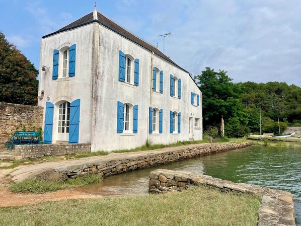 A two-story building with blue shutters and a stone wall.