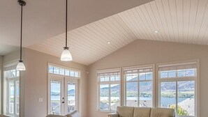 Ein geräumiges Zimmer mit hoher Decke, großen Fenstern, einem Esstisch und einer Couch.
