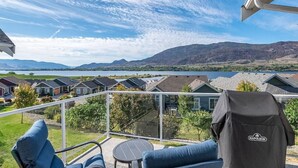 Ein Balkon mit Blick auf einen See und Berge, einem Grill und Sitzgelegenheiten im Freien.