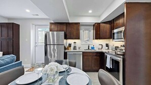 Una cocina moderna con gabinetes de madera oscura, electrodomésticos de acero inoxidable y un comedor listo para una comida.