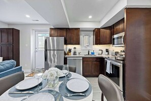 Una cocina moderna con gabinetes de madera oscura, electrodomésticos de acero inoxidable y un comedor listo para una comida.